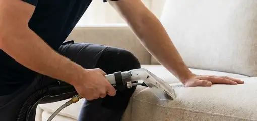 Professional upholstery cleaner deep-cleaning a fabric sofa with a handheld extraction tool, Akron, OH.